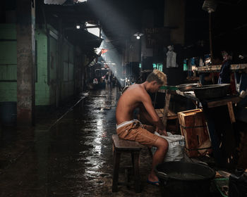 Side view of man sitting on chair in illuminated building