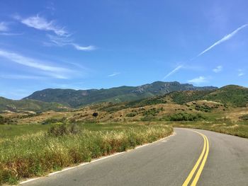 Scenic view of road by mountains against sky