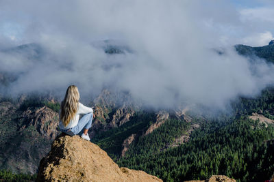 Low angle view of woman standing on mountain against sky