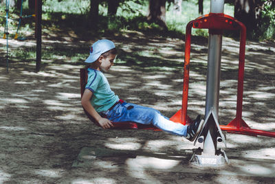 Side view of boy playing on seesaw at playground