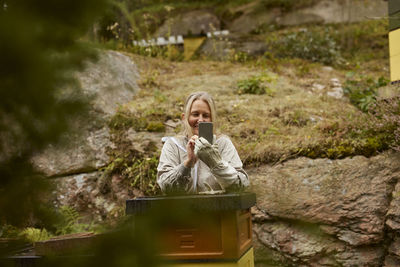 Bee-keeper photographing beehive