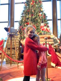 Portrait of cute girls standing against christmas tree