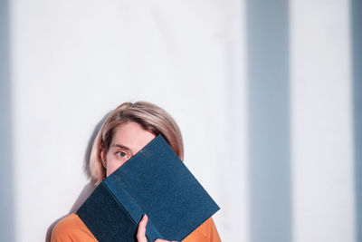 A young woman is yawning, looking at a book. tired after studying and learning