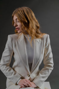 Portrait of young woman standing against gray background