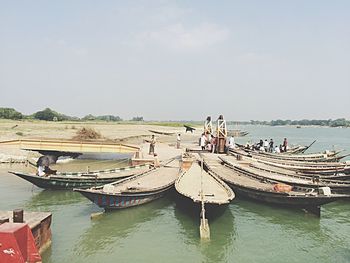 Boats moored in water against sky