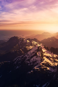 Aerial view of snowcapped mountains against sky during sunset