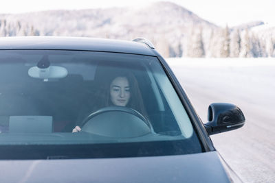 Woman driving in winter in a moutain area, while on road trip.