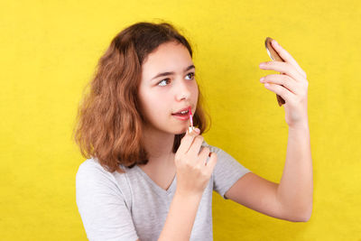 Portrait of a smiling young woman against yellow background