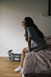 Depressed woman sitting on bed at home