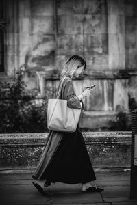 Woman holding umbrella while standing on mobile phone