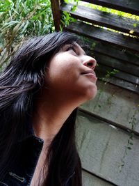 Low angle view of young woman looking up while standing outdoors