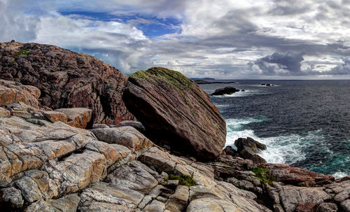 Scenic view of rocky beach against cloudy sky