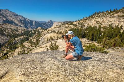 Man sitting on rock against mountains