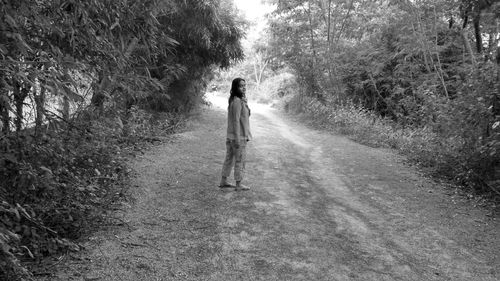 Rear view of woman walking on road amidst trees