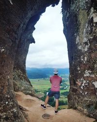 Rear view of man standing on rock by sea