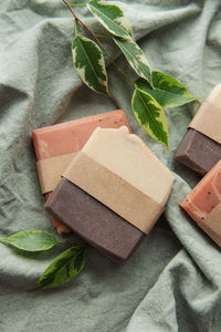 Assorted natural handmade soap bars and green leaves on a textile background