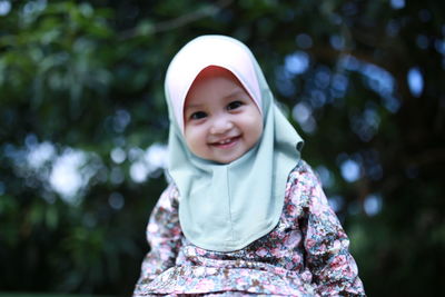 Portrait of smiling girl standing against tree