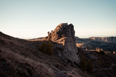 Full length of man climbing on rock against sky