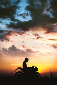 Silhouette man sitting on motorcycle against sky during sunset