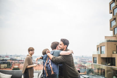 People standing on railing against sky in city