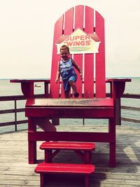Full length of boy on bench against built structure
