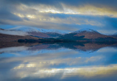 Scenic view of lake by mountains against sky