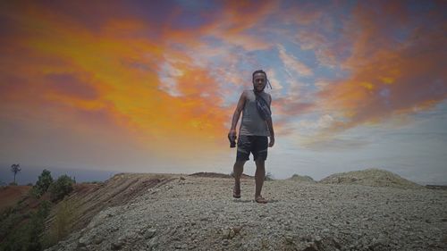 Full length of person standing on land against sky during sunset