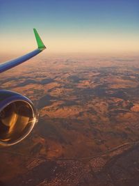 Aerial view of airplane wing over landscape against sky