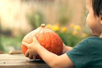 Midsection of man holding pumpkin against blurred background