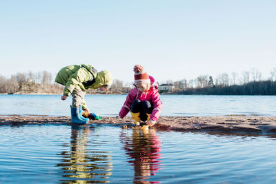 Siblings playing together at the sunny beach in winter in sweden