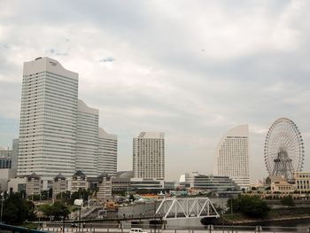 Skyscrapers in city against cloudy sky