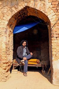 Full length of young man sitting against building