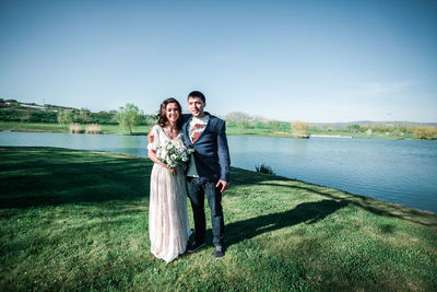 Young couple kissing on lake against sky