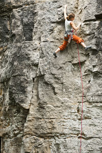Young woman climbing rock face in france