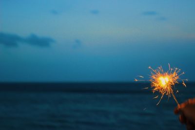 Firework display over sea against sky