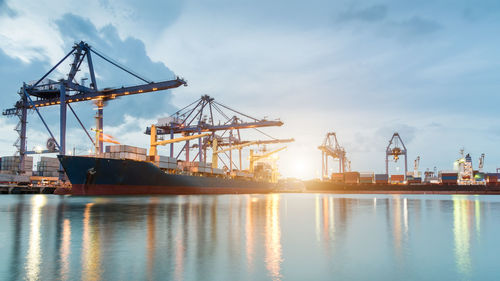 Cranes at commercial dock against sky