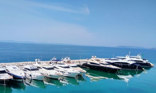 Sailboats moored on sea against sky