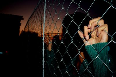 Close-up of hand on chainlink fence