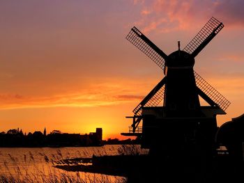 Silhouette traditional windmill against sky during sunset