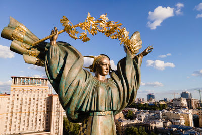 Statue in city against sky