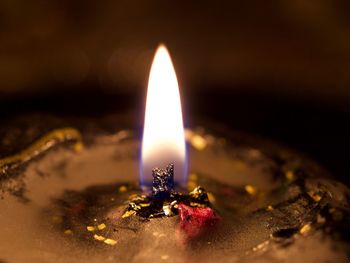 Close-up of lit candle in darkroom