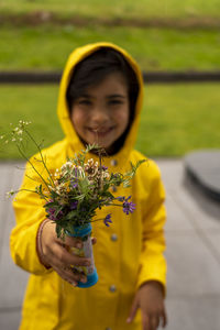 Portrait of smiling girl holding yellow flowering plant