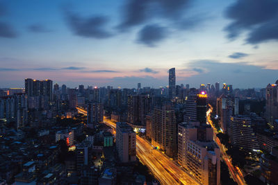 Aerial view of illuminated buildings in city against sky during dusk