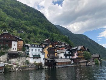 Houses by lake and buildings against sky