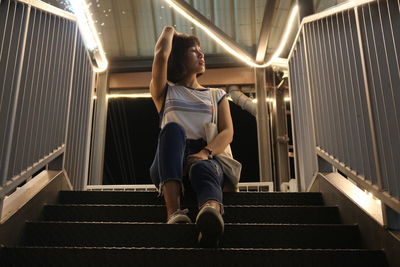Low angle view of woman sitting on staircase at night