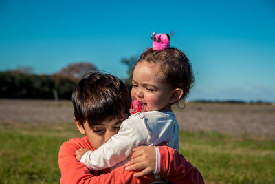 Close of brother carrying cute sister on land