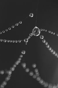 Close-up of water drop hanging against black background