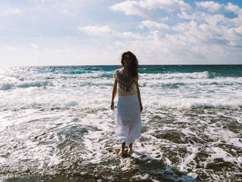 Woman wading in sea against sky