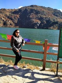 Portrait of young woman wearing sunglasses standing by railing