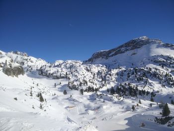 Scenic view of snowcapped mountains against clear blue sky